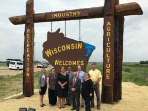 group of people standing in front of wisconsin welcomes you sign on highway